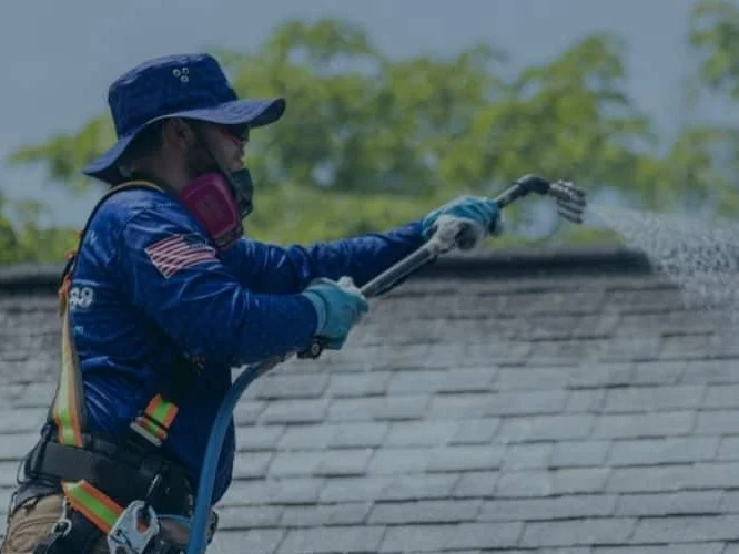 Blue Mountain Exteriors technician soft-washing a shingle roof